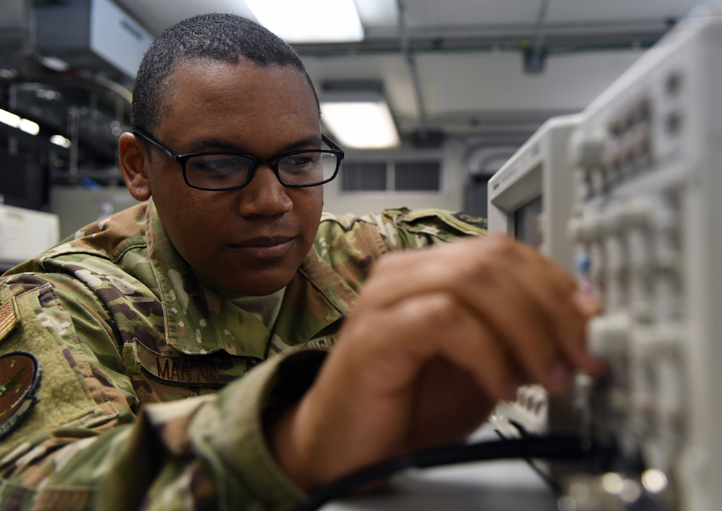 Apprenticeships and Workforce Readiness Tools - VPS Learning Soldier in camouflage uniform and glasses adjusting electronic equipment in a lab-like environment.