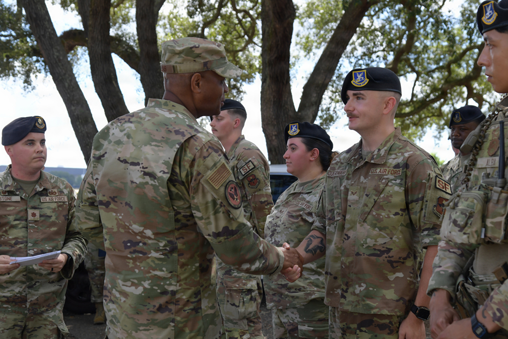 Agile Lethal Prepared Maj Gen Collins Engages with Team Keesler - VPS Learning Soldiers in camouflage uniforms shake hands during an outdoor ceremony with trees in the background, showing respect or congratulations to a colleague.